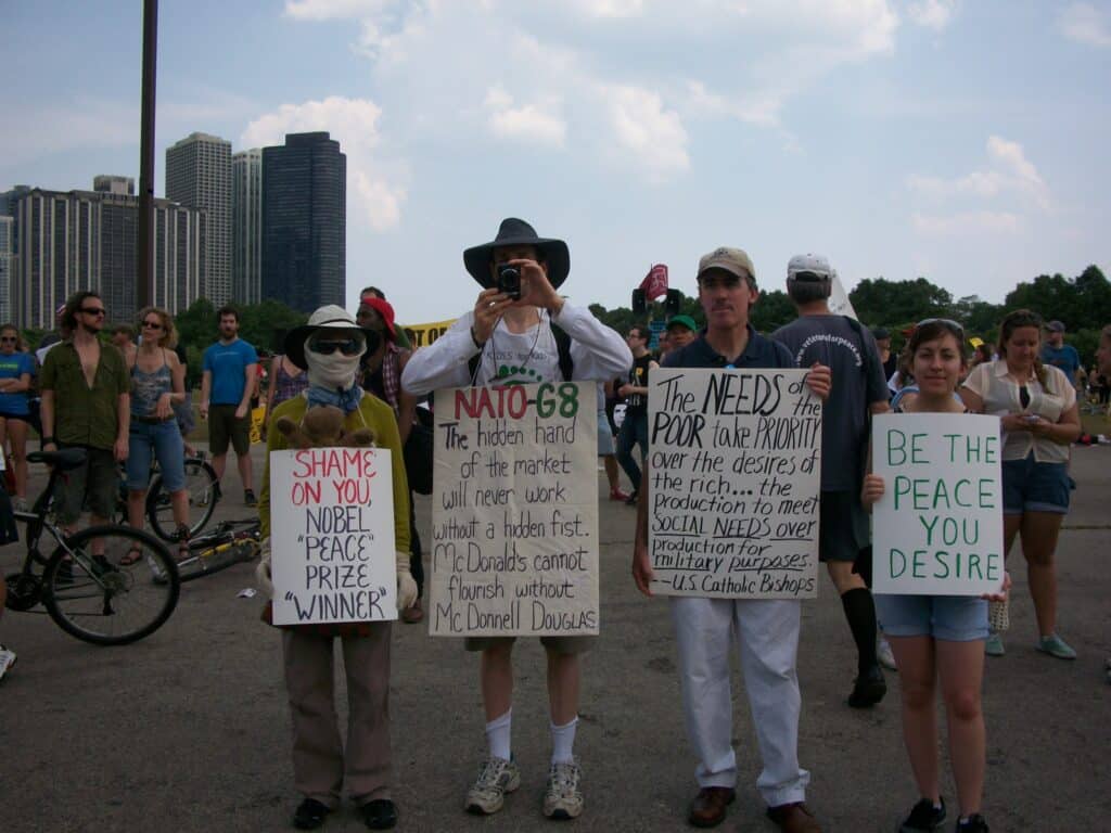 Four demonstrators hold signs protesting at the NATO Summit in Chicago.