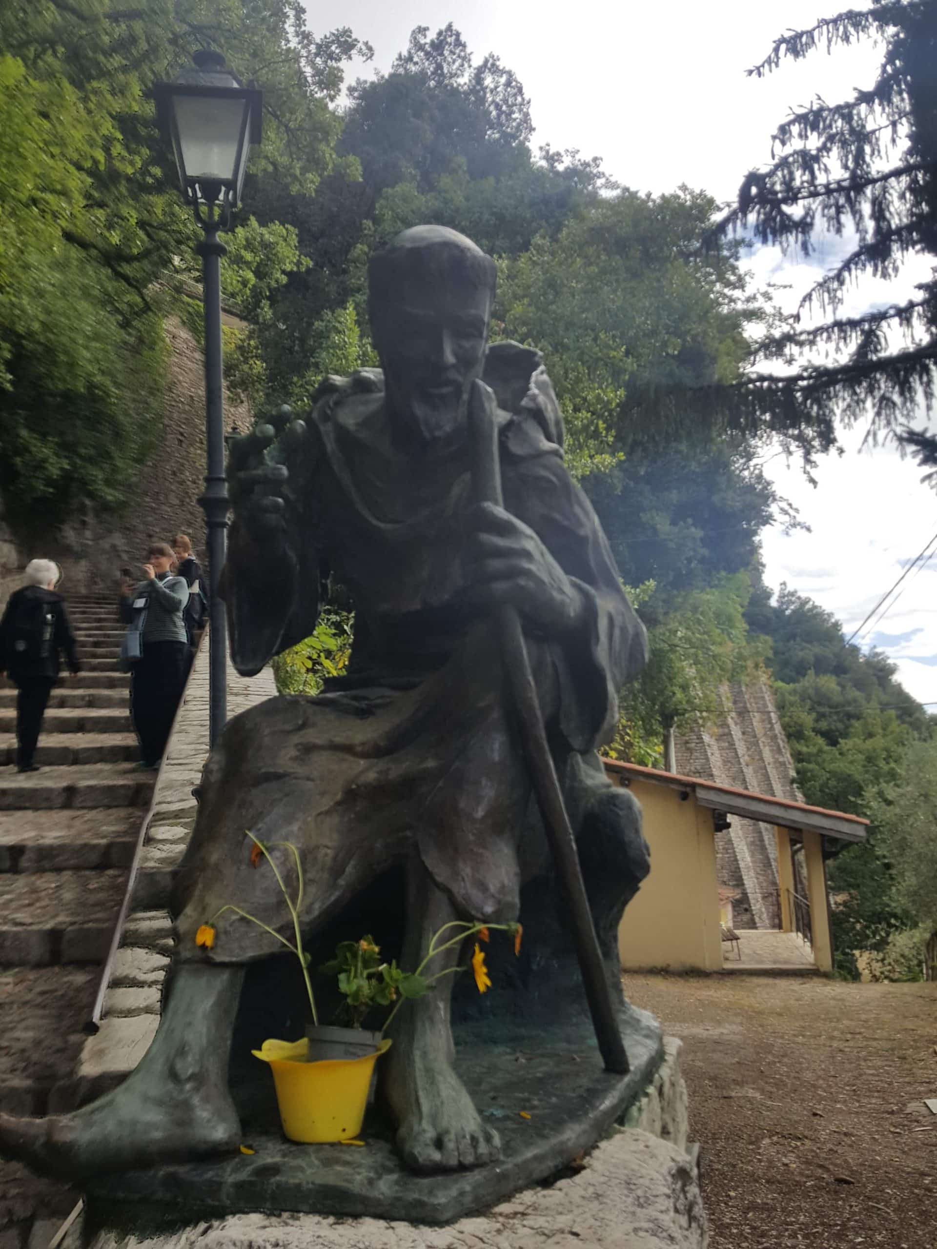 statue-man-robe-staff-stone-steps-lam post-yellow- pot-flowers