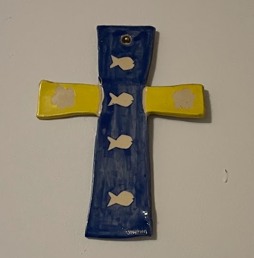 blue and yellow ceramic cross featuring white fish