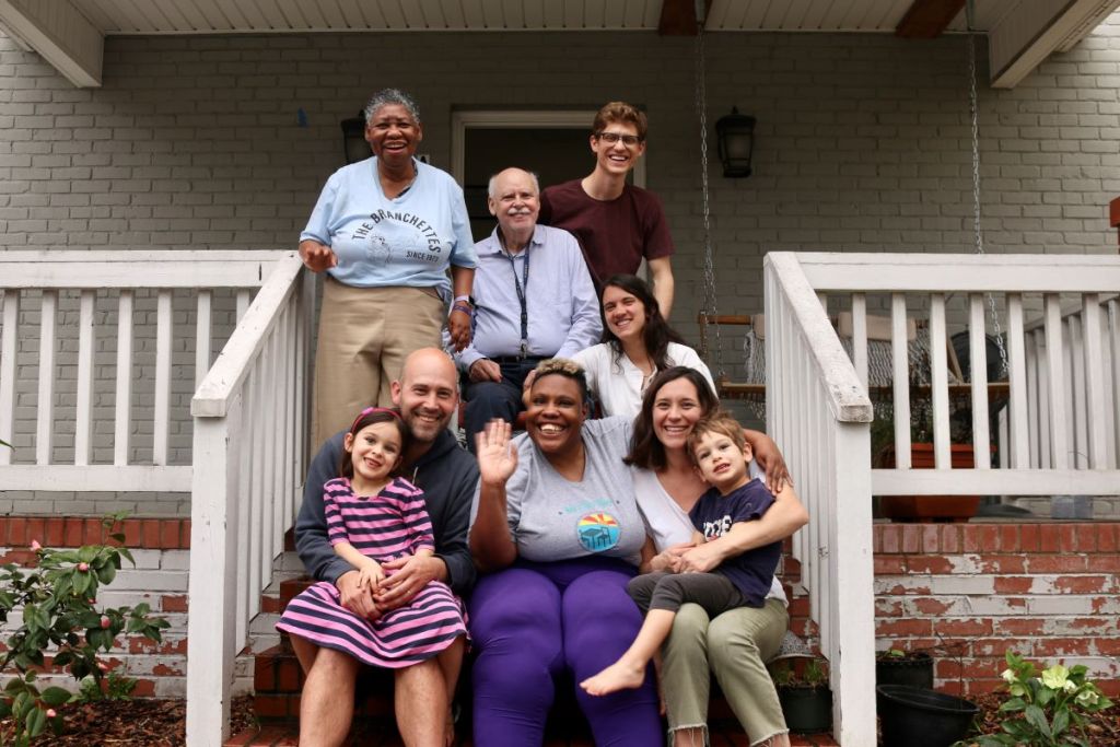 Seven adults and two children sitting on front porch