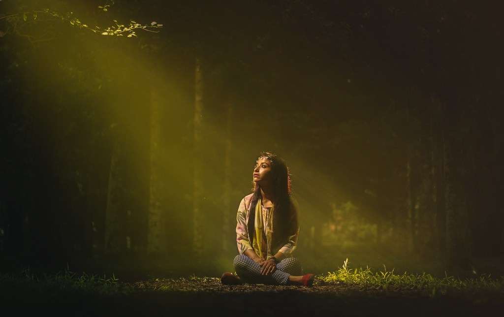 woman in the forest sitting in the sunlight, contemplating one word by pexels on pixaby