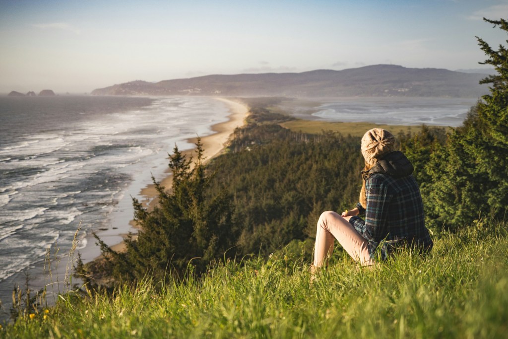 Woman on a hill overlooking trees and water