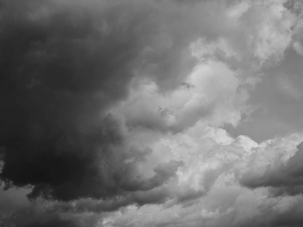 A moody black and white photograph capturing stormy clouds in the sky.