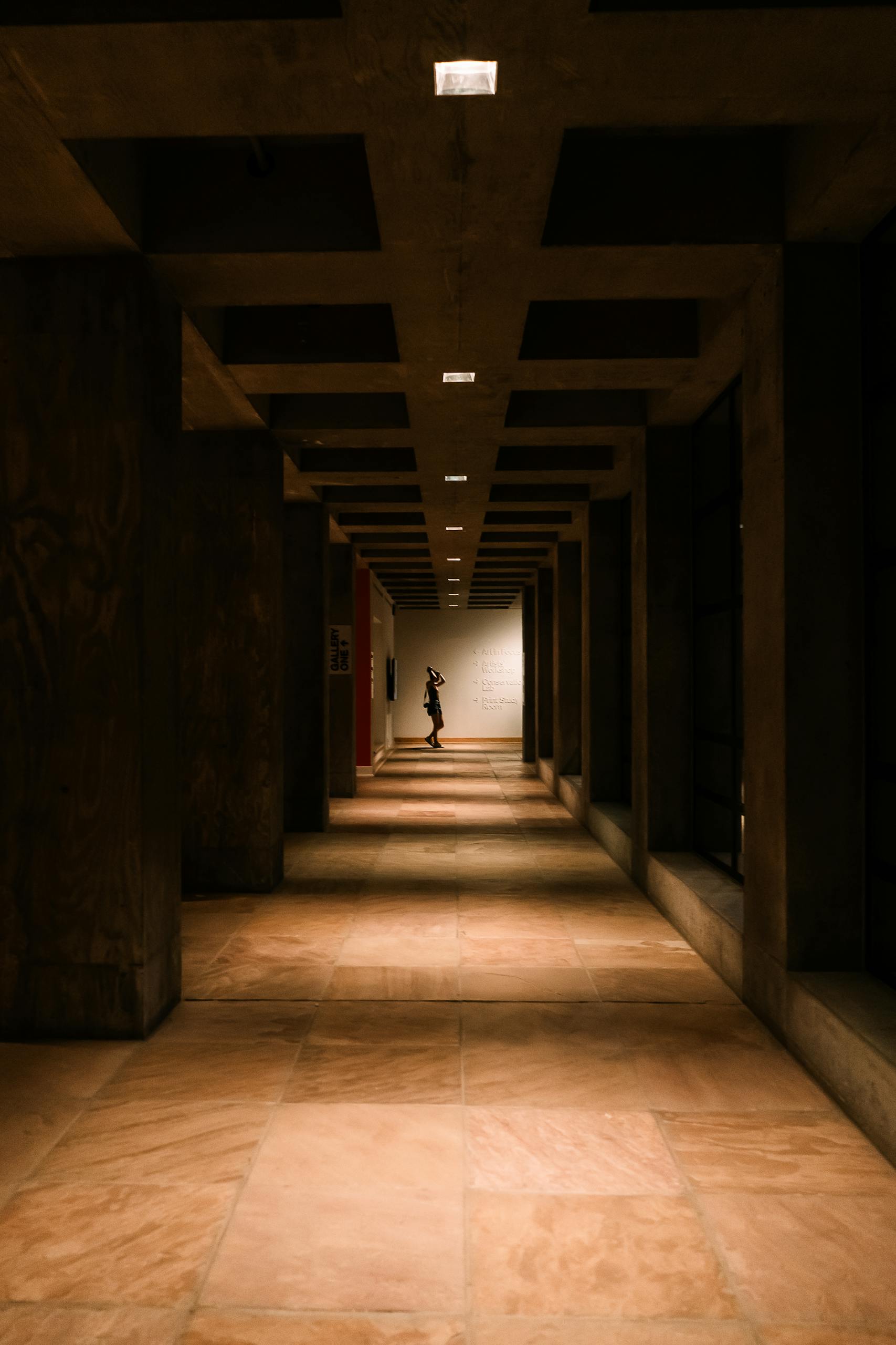 A moody, dimly lit corridor with a solitary figure standing at the end, Tempe, AZ.